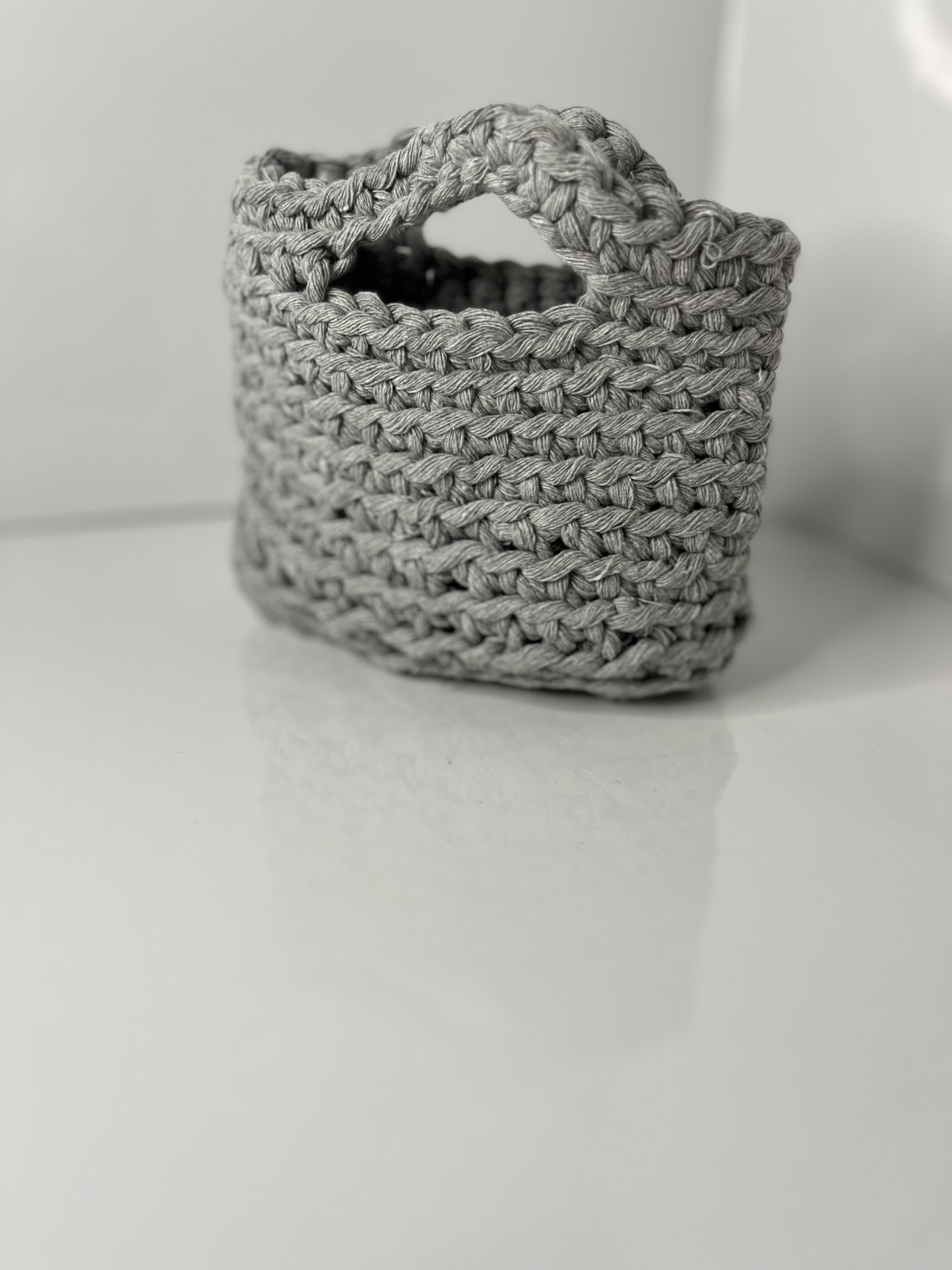 Another angled shot of the bag highlights its cylindrical form and woven material against the smooth background.