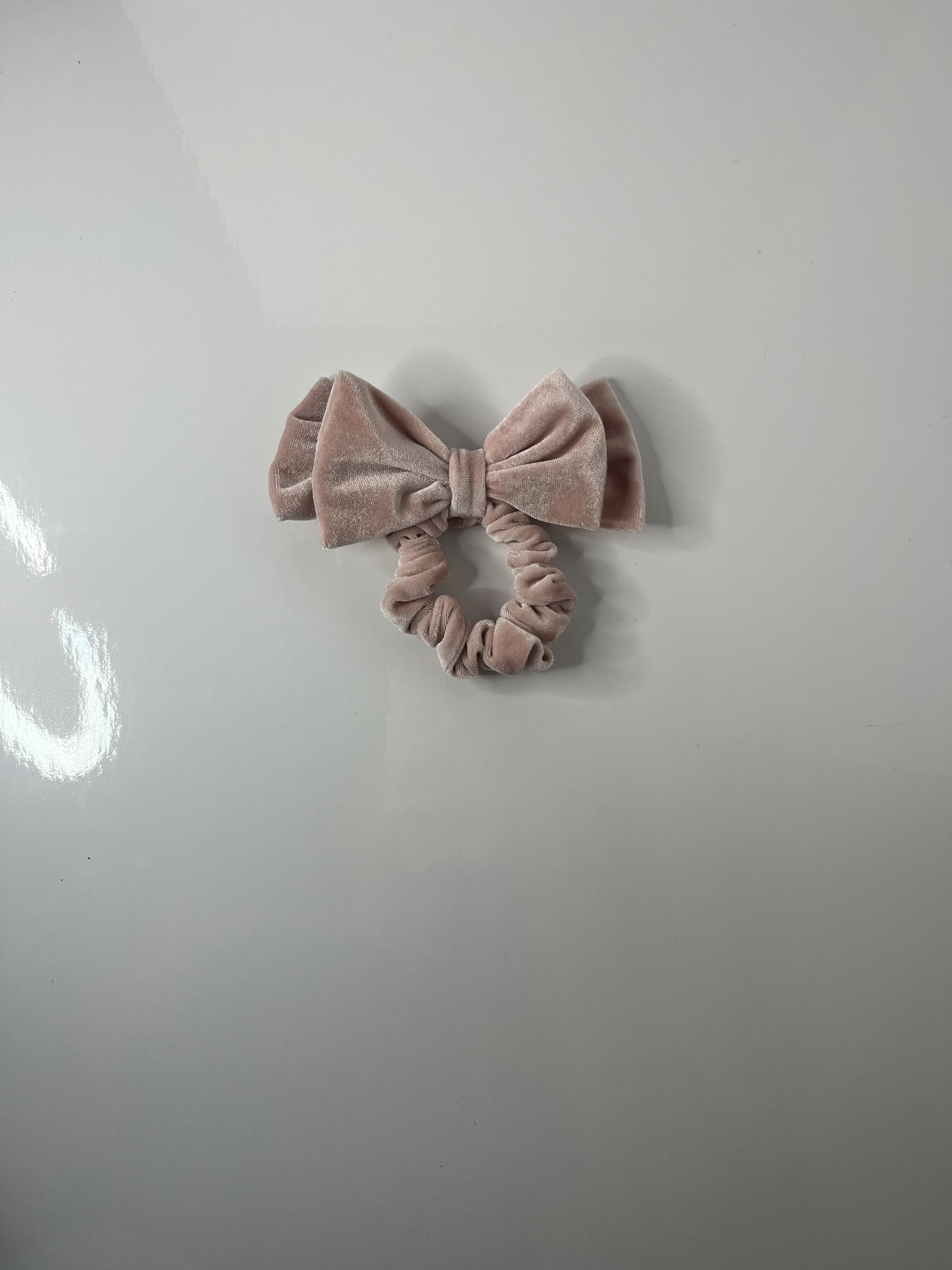 Another angled shot of the scrunchie captures the texture and circular form with the bow extending outward.