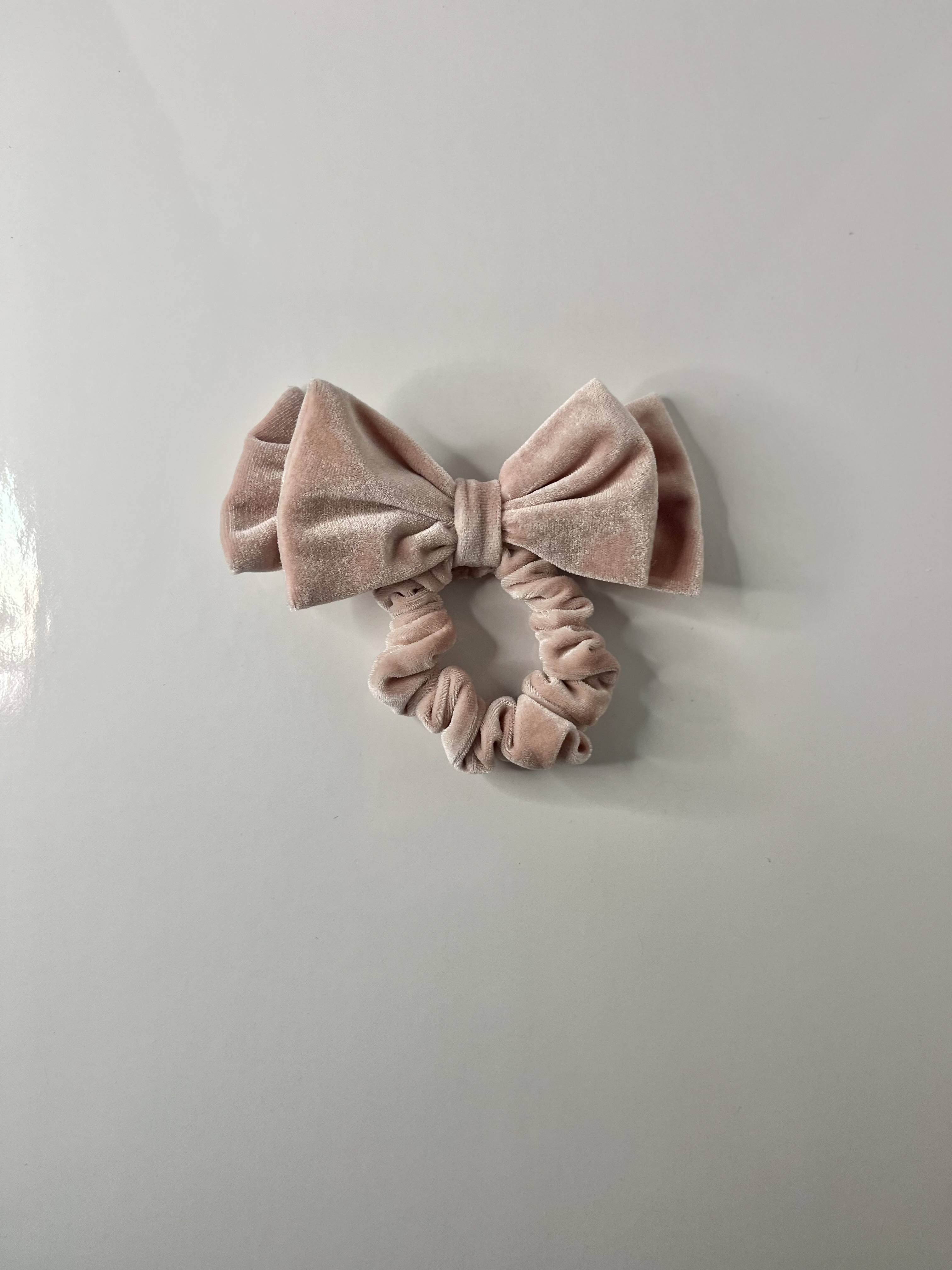 The scrunchie is displayed from above, showing its circular form and bow attachment from a top-down perspective.