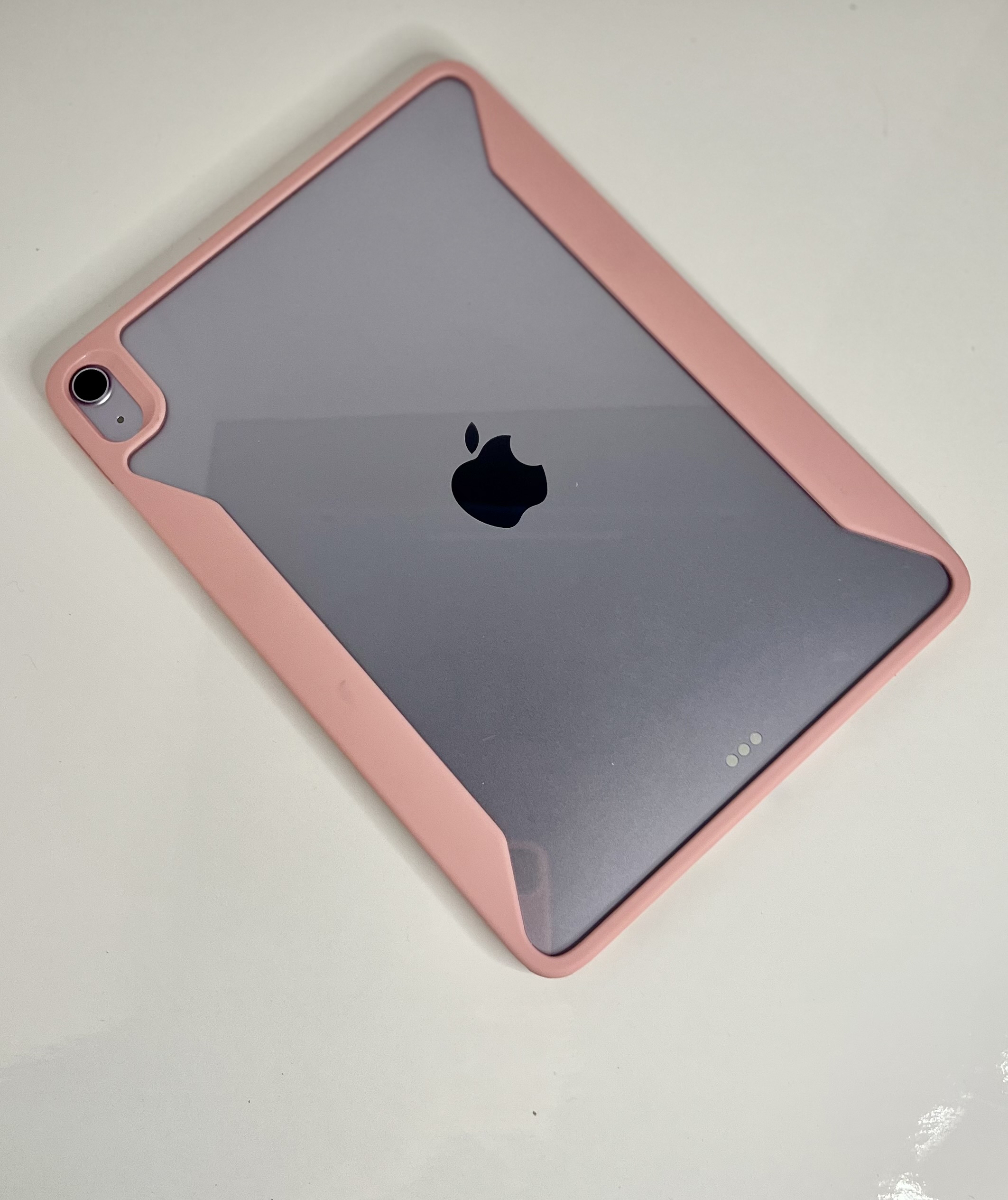 An iPad with a pink protective case is laid flat, showing its Apple logo and corner details.