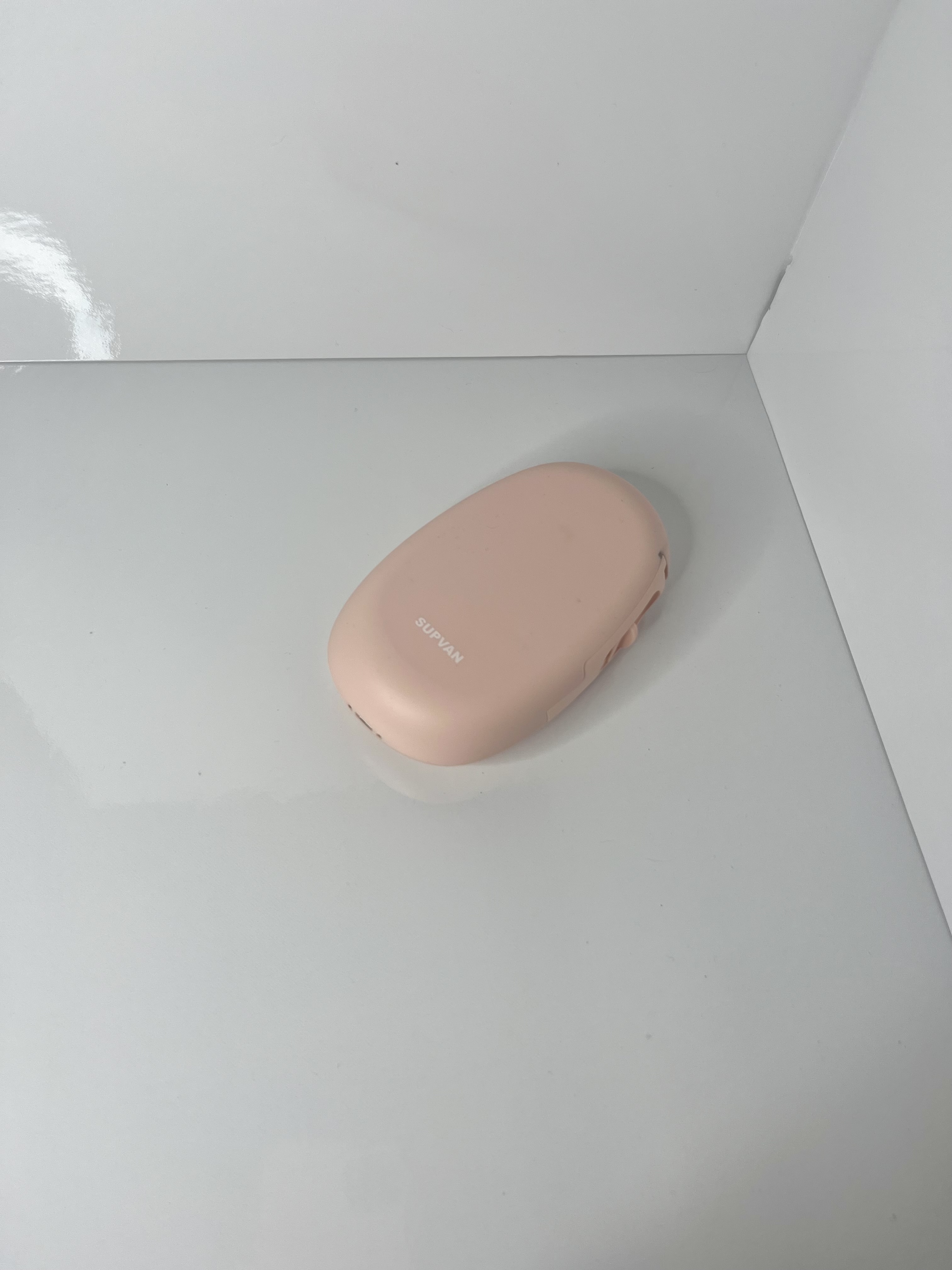 A pale pink portable sticker printer rests on its side, showing a smooth oval body with the SUPVAN logo.
