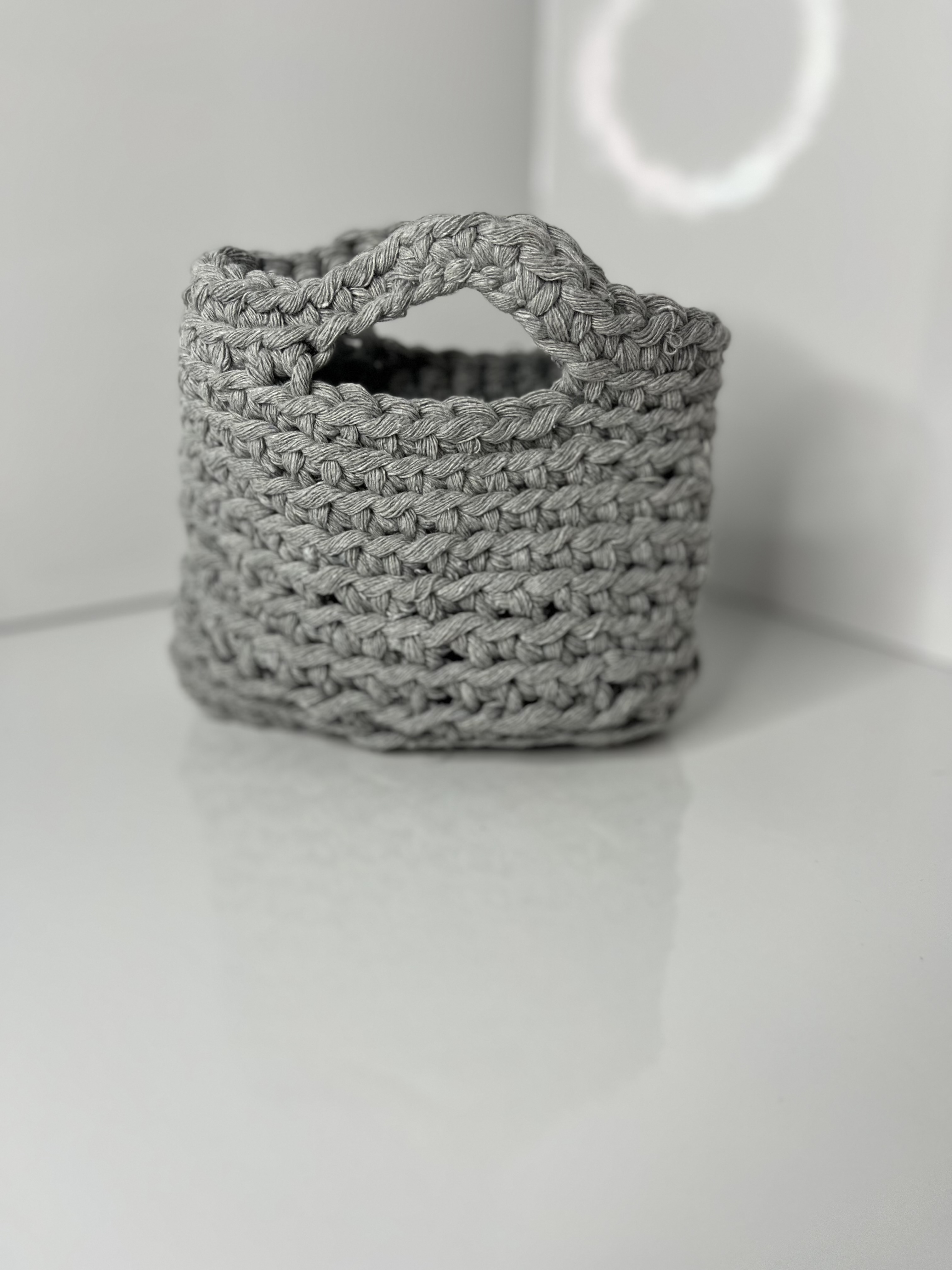 The crocheted bag is presented at an angle, revealing its textured stitch pattern and integrated handle.